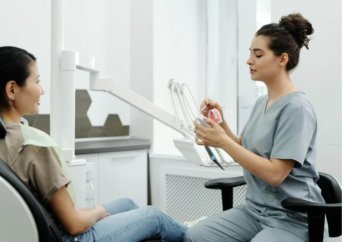 Dental professional explaining a full mouth dental implant model to a patient while discussing treatment options and costs.