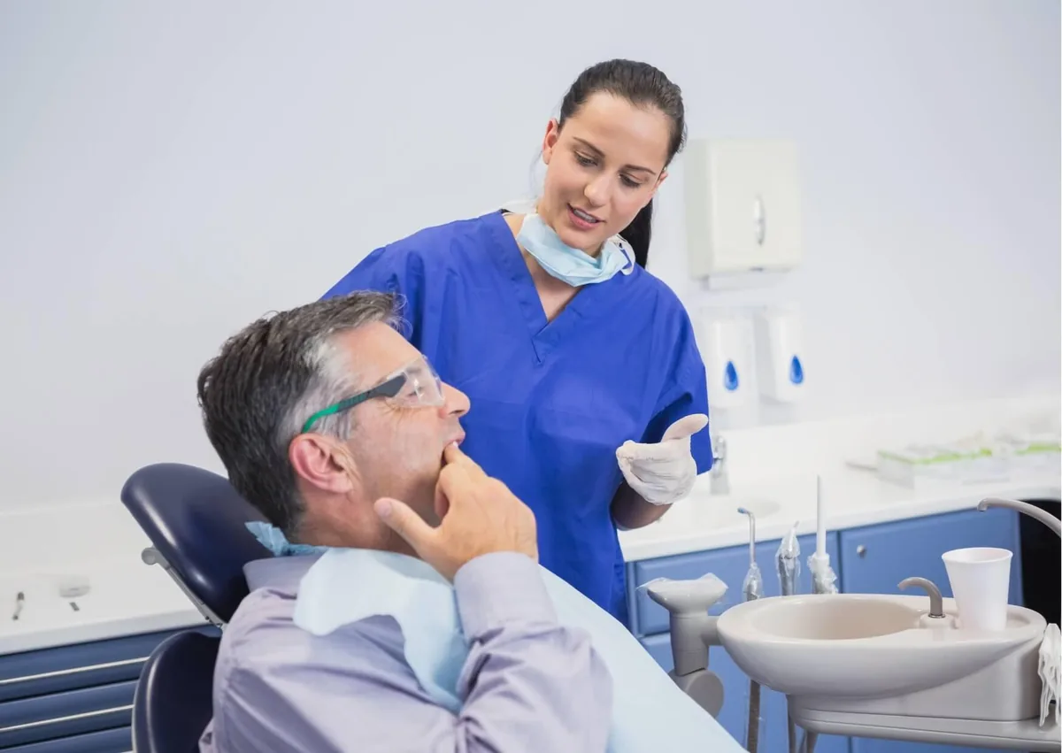 Dental professional discussing gum recession symptoms and treatment options with a patient experiencing oral discomfort.