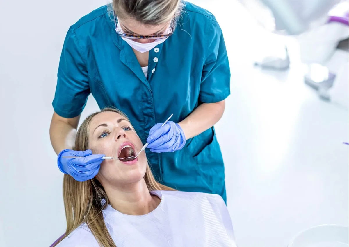 Dental professional examining a patient’s mouth to evaluate a canker sore and its healing progress.