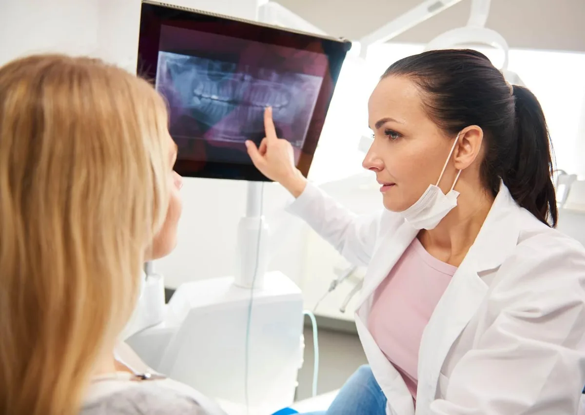 Dentist reviewing a dental X-ray with a patient during an evaluation for affordable dental implants.
