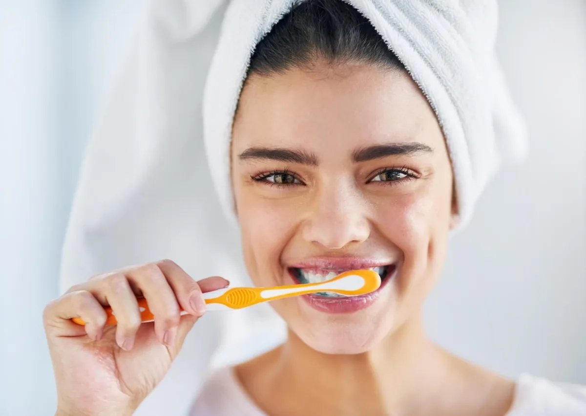 Woman brushing her teeth as part of a daily routine for preventing cavities.