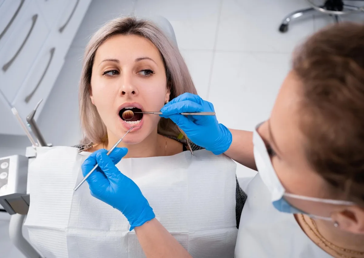Dentist examining a patient’s mouth for signs and symptoms of oral thrush.