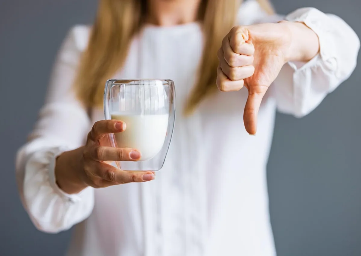 Woman avoiding milk as part of dietary precautions after dental implant surgery.