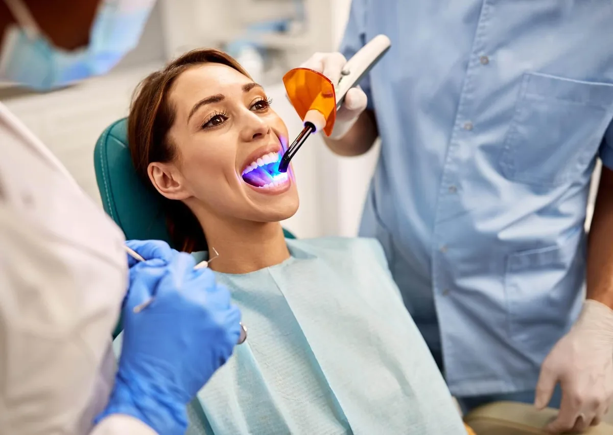 Dentist performing a cosmetic dental procedure on a patient, illustrating teeth bonding treatment and its associated cost.